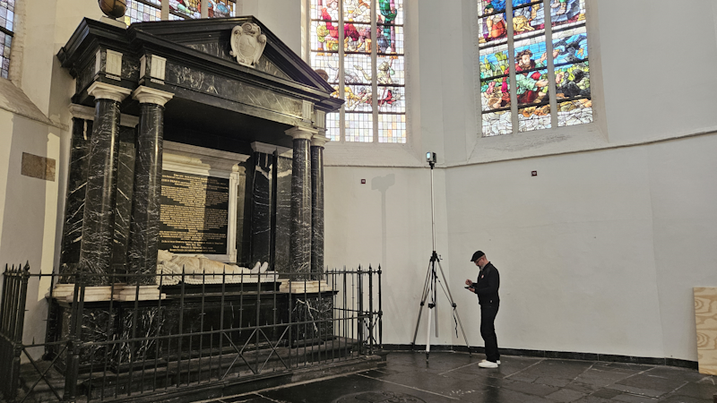 Een medewerker van PelserHartman scant het grafmonument van Piet Hein met een Leica RTC360 3D laserscanner, omgeven door glas-in-loodramen in de Oude Kerk in Delft.